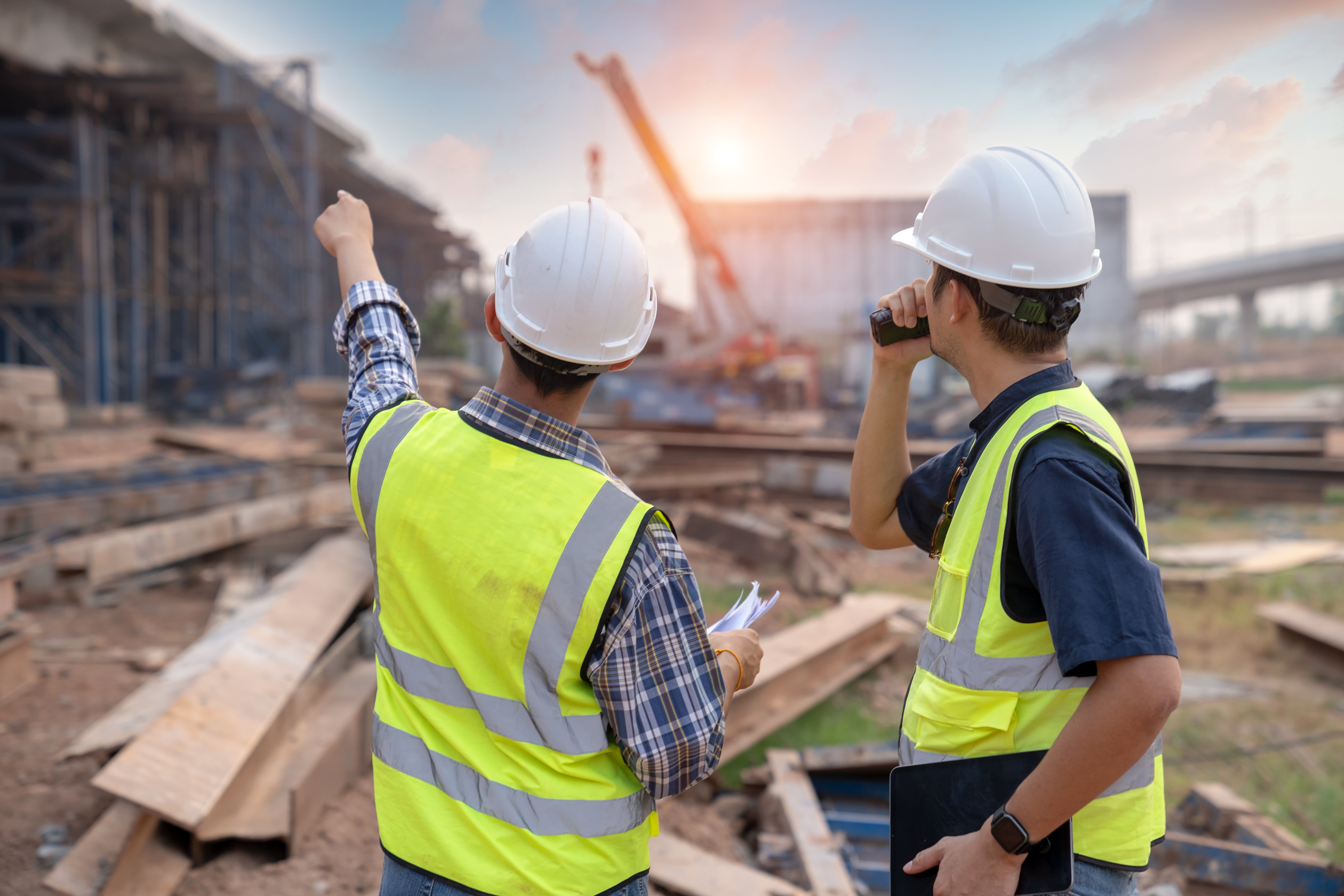 Construction workers on a commercial jobsite reviewing plans and performing skilled trade work.